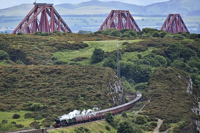 EDINBURGH, SCOTLAND - JUNE 25: The Flying Scotsman steam train travels across the Forth Bridge, as it makes a journey through Fife on June 25, 2021 in Edinburgh, Scotland. The train will spend two days in Edinburgh where passengers will take a journey over the Forth Bridge in 1960's open carriages with large picture windows. (Photo by Jeff J Mitchell/Getty Images)