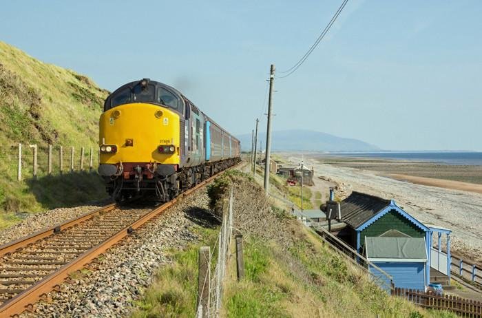 The 14.37 2C41 Barrow to Carlisle service was running 50 minutes late on Thursday 11 June 2015, providing satisfactory sunlight on the 'nose' of DRS 37609 as it passes a splendidly restored and maintained period beach chalet at Braystones on the Cumbrian Coast. ©Gordon Edgar /Rail Photoprints